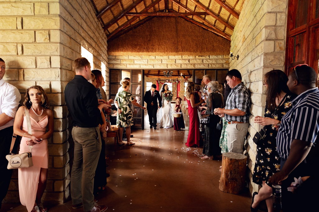 A bride and groom entering the thatched stone venue at Goldfields between their guests.